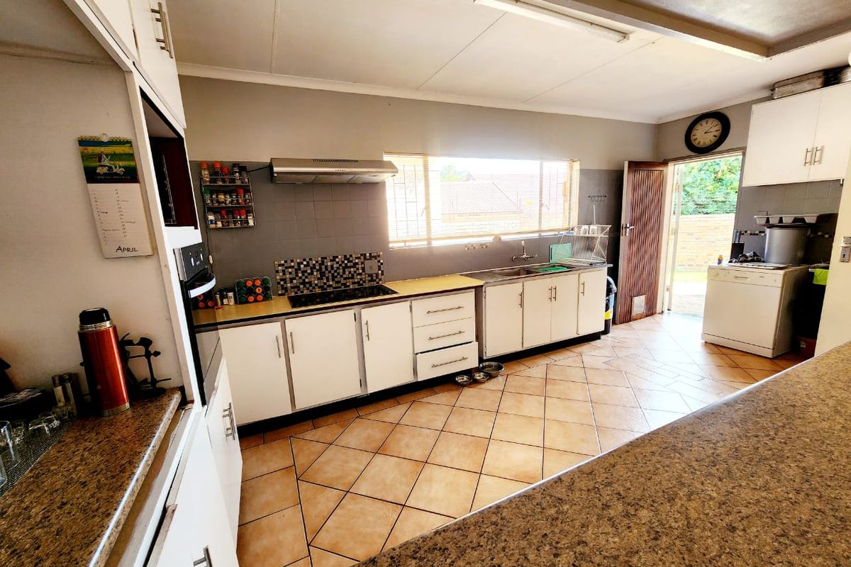 Functional kitchen featuring white cabinetry, laminate countertops, built-in oven, hob, and extractor fan with direct access to the rear exterior.