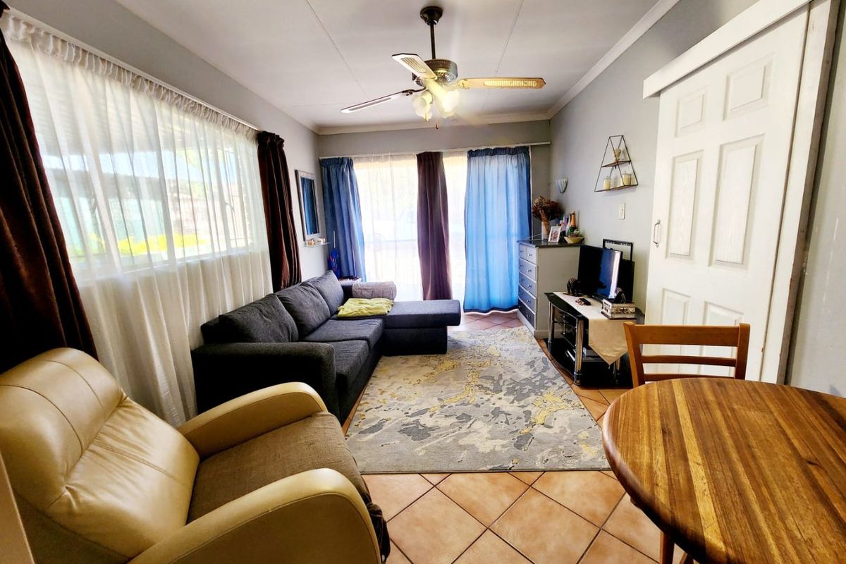 A functional living room featuring tiled flooring, a ceiling fan, and sliding door access, providing a comfortable and practical living space.