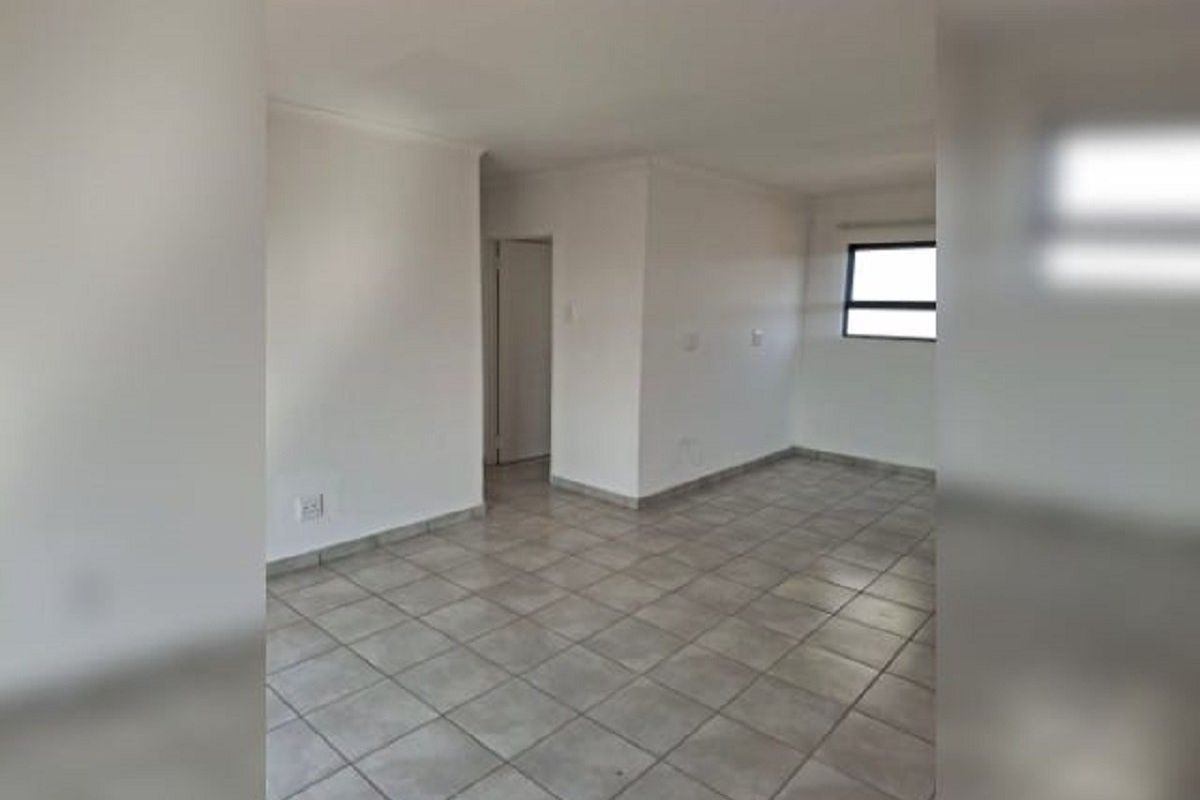 An empty, neutrally painted living area featuring tiled flooring and a window, providing a blank canvas for interior design.