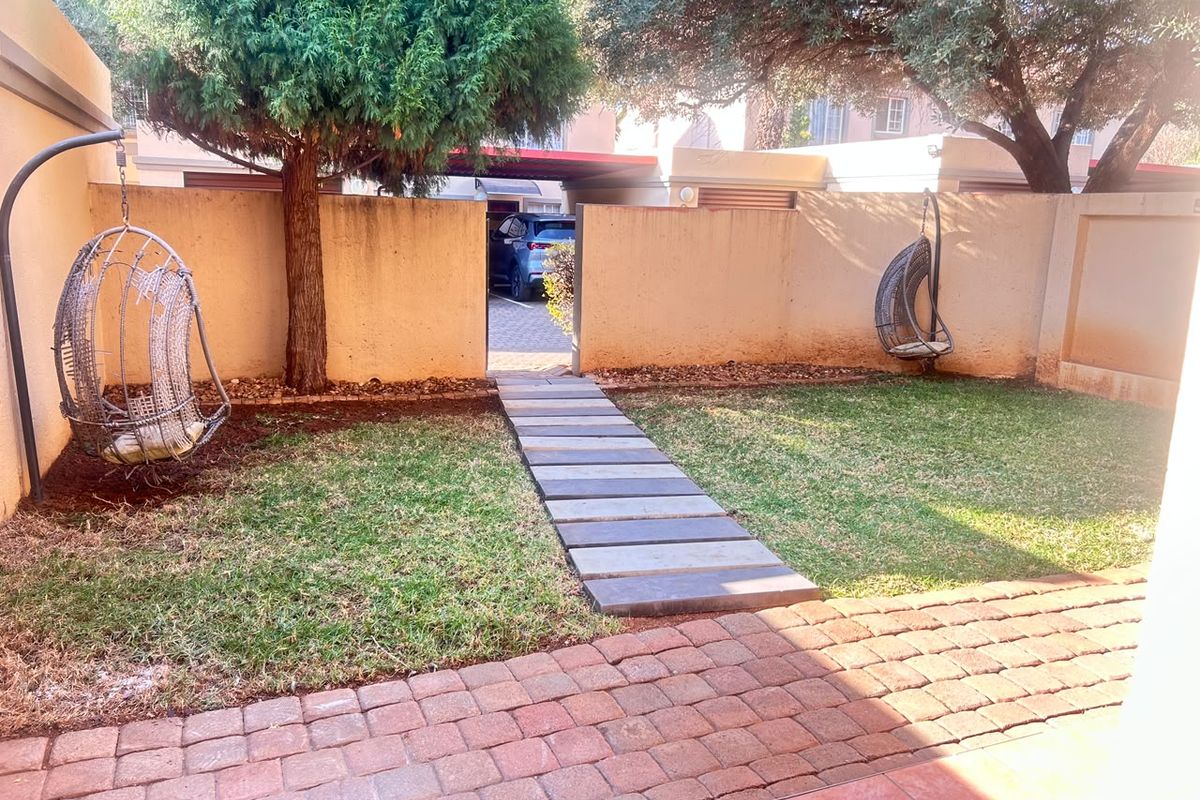 A private rear garden featuring a brick patio, paved walkway, and boundary walls, offering a functional outdoor space for the townhouse.
