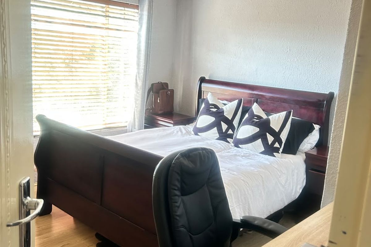 A bedroom featuring laminate flooring, recessed downlighting, and venetian blinds, viewed from the doorway.
