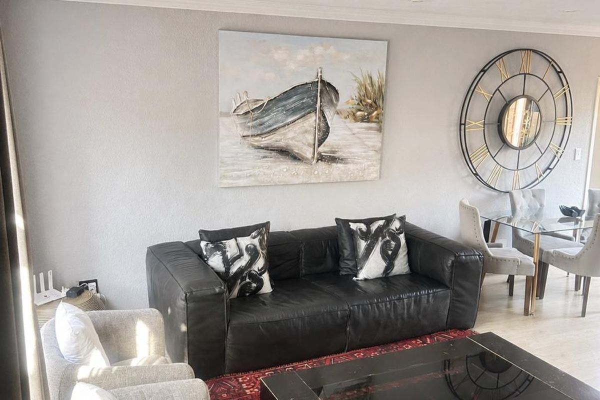 A well-maintained living room featuring neutral walls, recessed downlighting, and light-toned laminate flooring, creating a comfortable and inviting space.