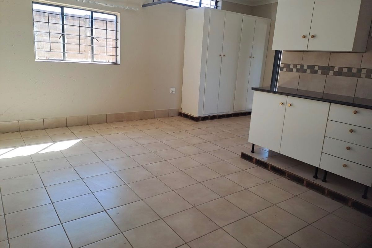 An empty kitchen area featuring tiled flooring, built-in white cabinetry, and a tiled backsplash, awaiting modern updates to enhance its functionality and aesthetic appeal.