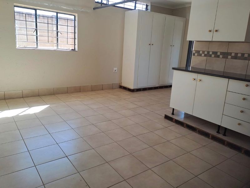 An empty kitchen area featuring tiled flooring, built-in white cabinetry, and a tiled backsplash, awaiting modern updates to enhance its functionality and aesthetic appeal.