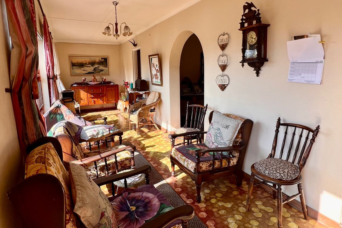 A sunlit living room featuring a classic archway, patterned tiled flooring, and traditional ceiling lighting, offering a warm and inviting atmosphere.