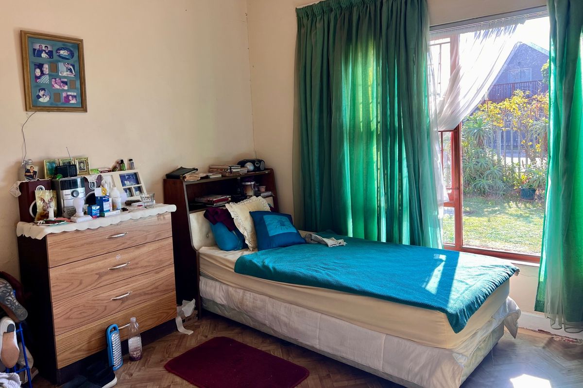 A bedroom featuring parquet flooring and a large sliding glass door providing natural light and garden access.