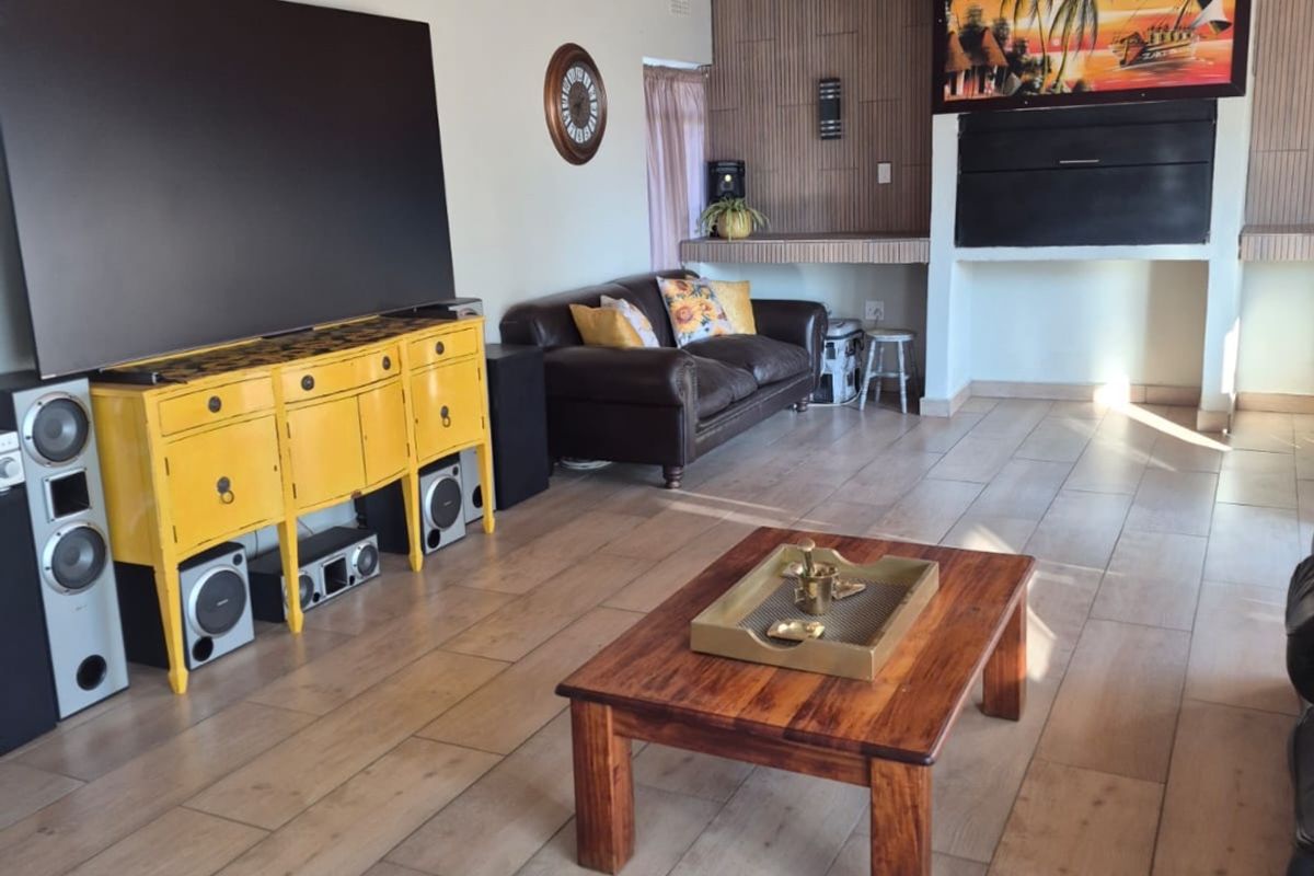 A spacious living room featuring a wood-paneled ceiling, tiled flooring, and a built-in fireplace, offering a comfortable and functional living space.