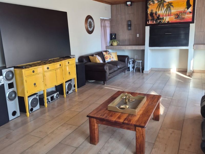 A spacious living room featuring a wood-paneled ceiling, tiled flooring, and a built-in fireplace, offering a comfortable and functional living space.