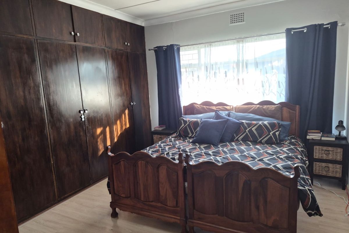 A bedroom featuring laminate flooring and extensive dark wood built-in cupboards, providing ample storage space.