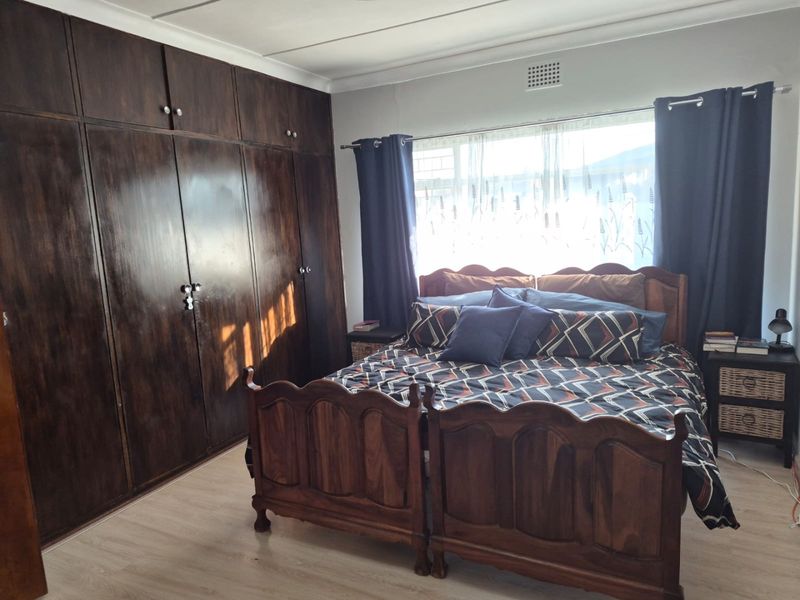 A bedroom featuring laminate flooring and extensive dark wood built-in cupboards, providing ample storage space.