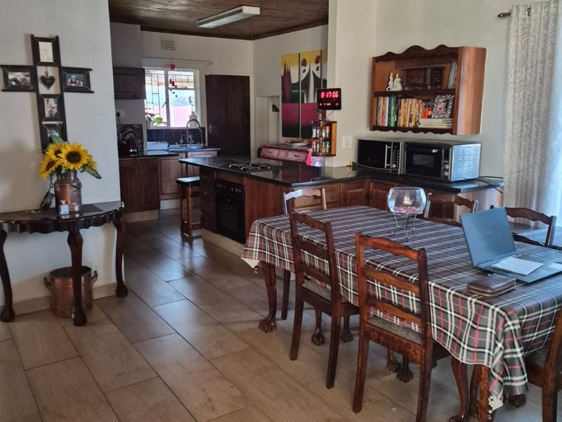 Open-plan kitchen and dining area featuring timber ceilings, tiled flooring, and a central kitchen island with built-in cooking appliances.