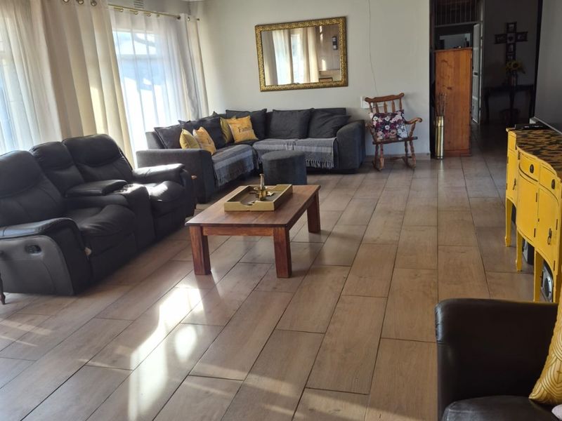 Spacious living room featuring timber-look tile flooring and a distinctive timber-clad ceiling with recessed lighting.