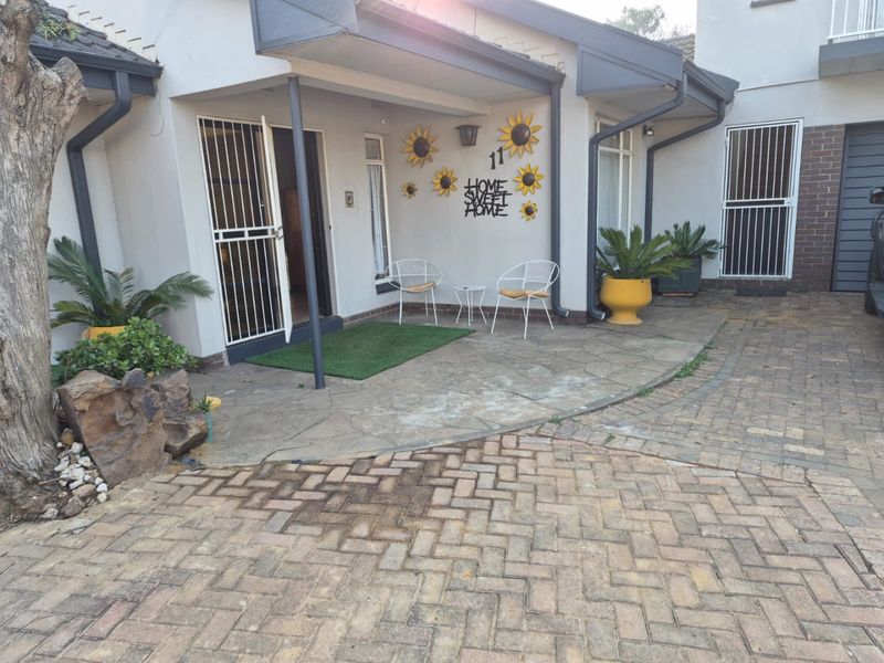 Front entrance area featuring a covered patio, security gate, and paved driveway access.