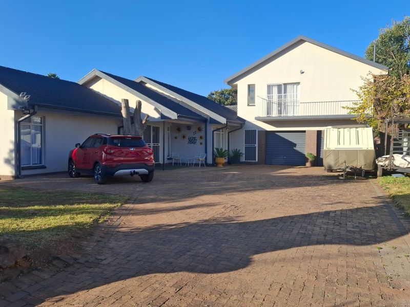 Front exterior view of a multi-level residential property featuring a paved driveway, integrated garage, and an upper-level balcony.