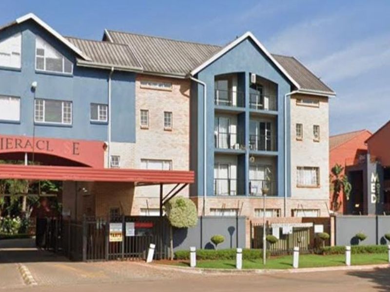 Front elevation of the Rivieraclose apartment complex featuring a gated entrance, multi-story brick facade, and private balconies.