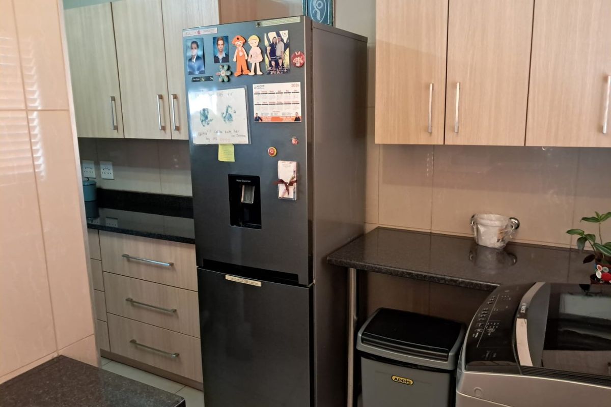 A functional kitchen area featuring light wood-tone cabinetry, dark granite countertops, and tiled wall finishes.