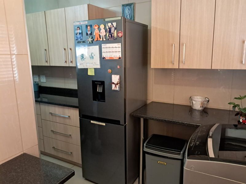 A functional kitchen area featuring light wood-tone cabinetry, dark granite countertops, and tiled wall finishes.