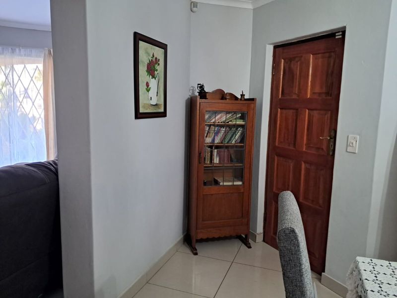A functional hallway area featuring tiled flooring and a traditional wooden door, providing access to adjacent living spaces.