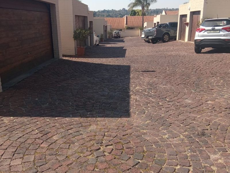 A view of the townhouse complex driveway featuring cobblestone paving and multiple garage access points.