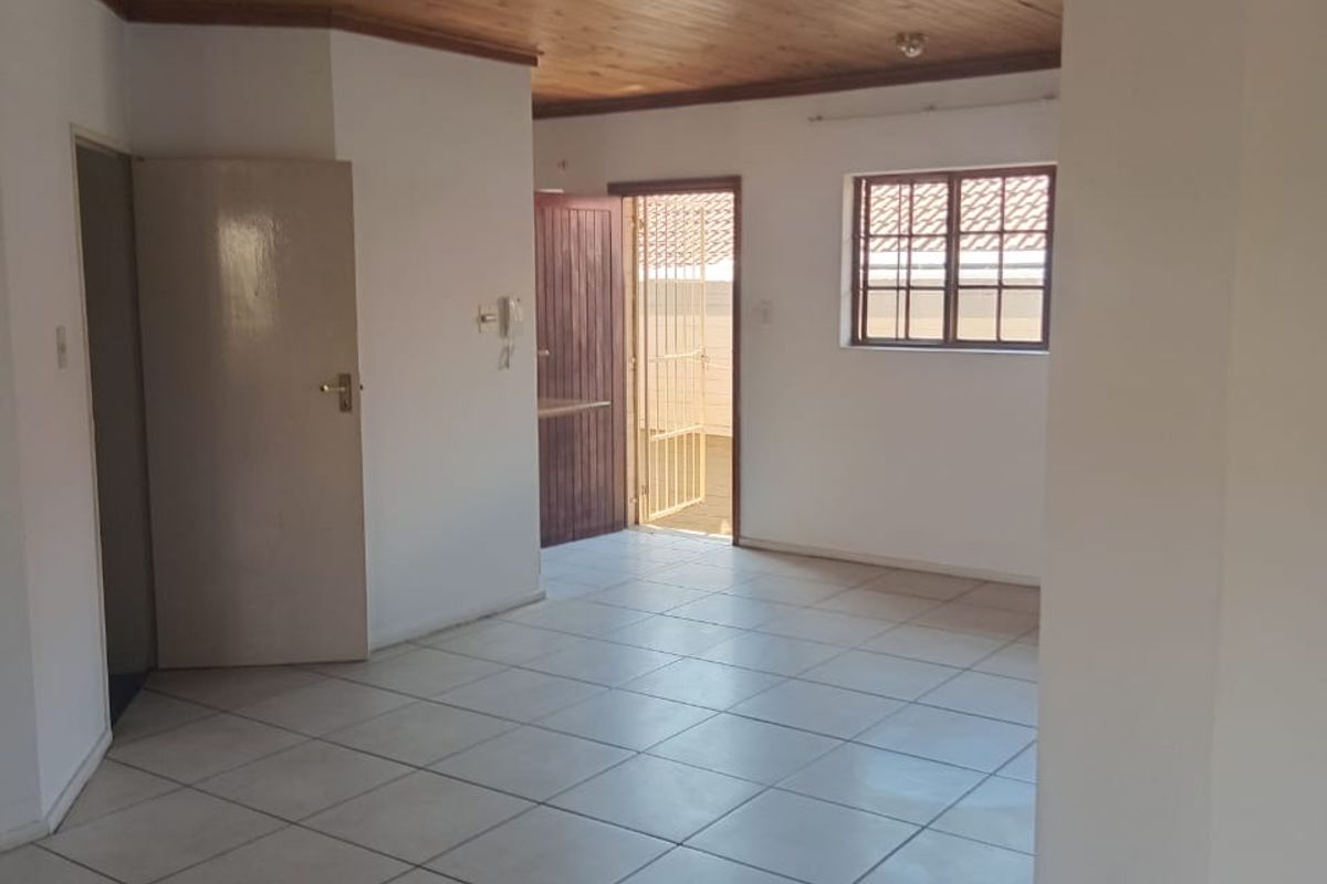An empty living area featuring ceramic floor tiles and a timber tongue and groove ceiling, providing a neutral canvas for potential interior updates.