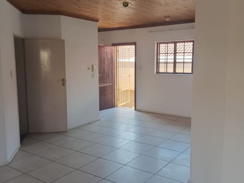 An empty living area featuring ceramic floor tiles and a timber tongue and groove ceiling, providing a neutral canvas for potential interior updates.
