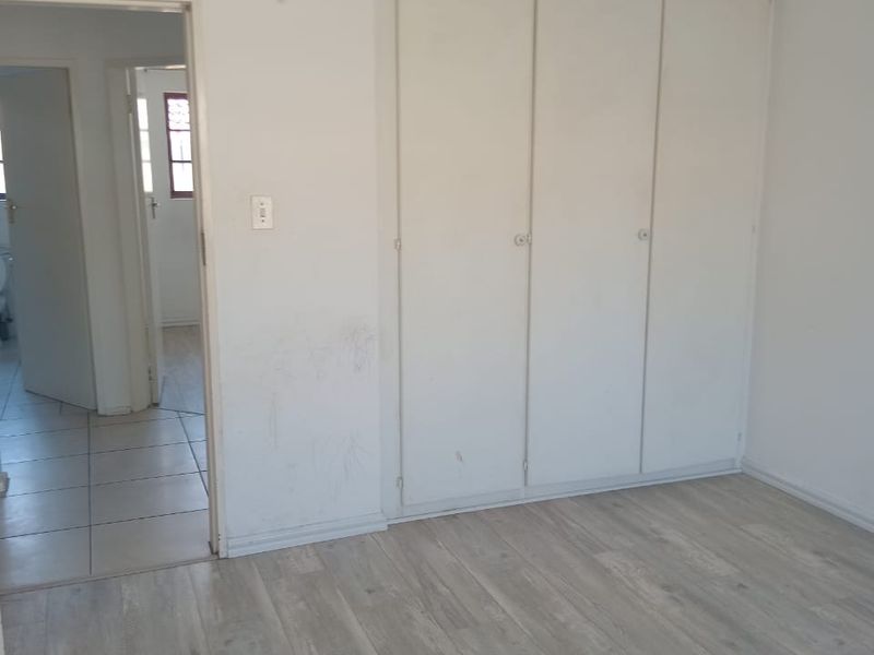 An empty bedroom featuring light-toned laminate flooring and built-in cupboards, providing a clean, neutral canvas for personalization.