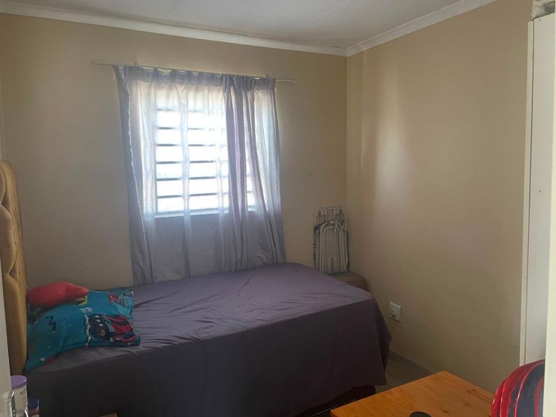 A standard bedroom featuring a window with security bars and neutral wall finishes.