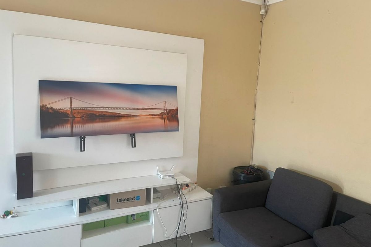 A living room area featuring a built-in media unit and wall-mounted display, requiring minor cosmetic updates to wall finishes and cable management.
