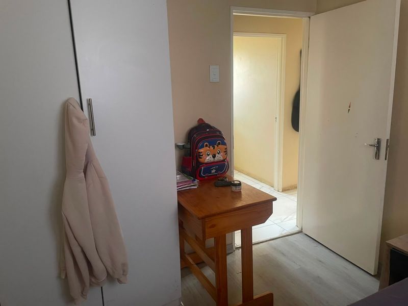 A bedroom featuring laminate flooring and a built-in wardrobe, providing functional storage space within the home.