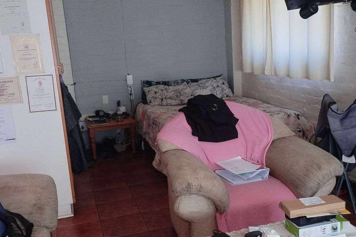 A bedroom featuring tiled flooring and an exposed brick wall, currently in need of cosmetic updates and maintenance to improve its overall condition.