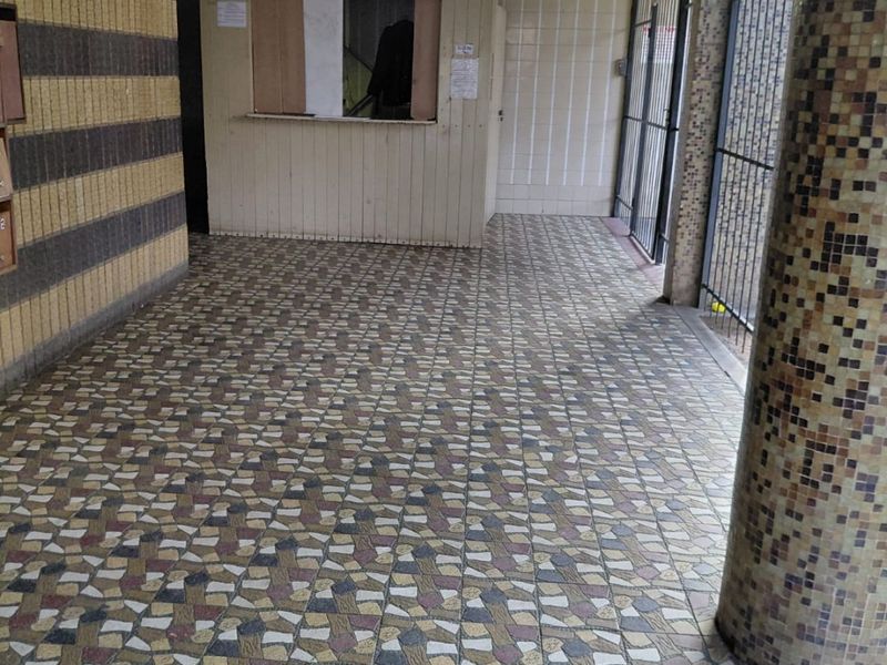 Entrance lobby area featuring mosaic tiled pillars, patterned floor tiles, and a built-in reception kiosk with security gate access.