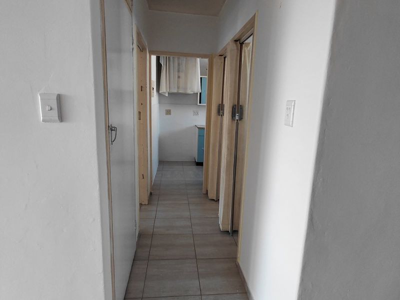A functional hallway featuring tiled flooring and built-in storage, providing access to adjacent rooms within the apartment.