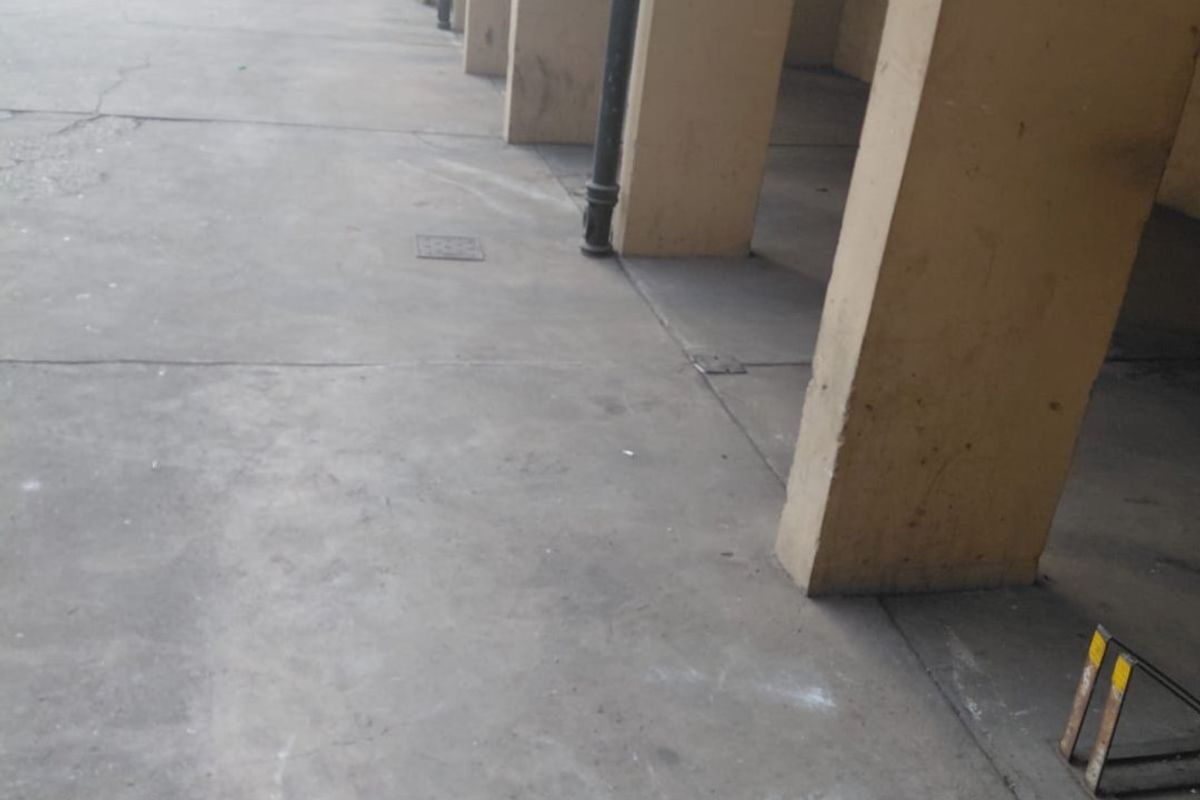 A covered parking area featuring concrete pillars and flooring, showing signs of wear and surface staining.