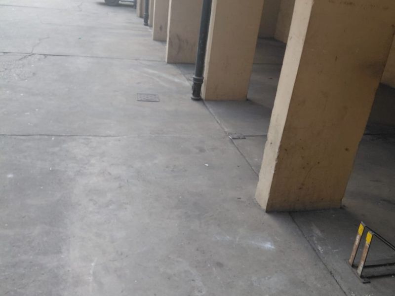 A covered parking area featuring concrete pillars and flooring, showing signs of wear and surface staining.