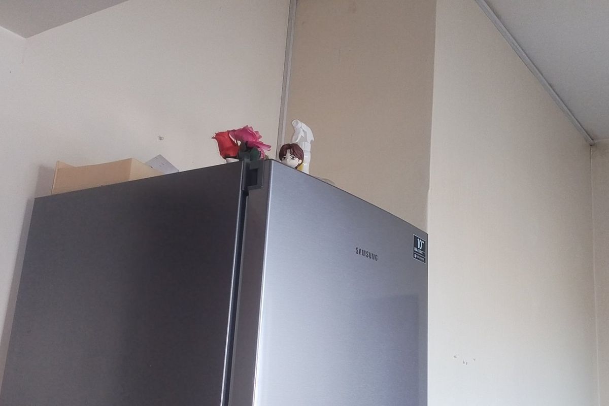 A close-up view of a kitchen corner featuring a stainless steel refrigerator against a plain wall.