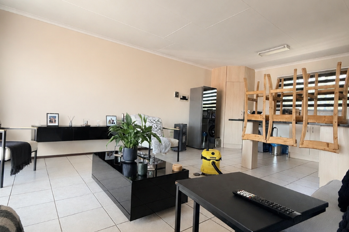 Open-plan living and dining area featuring neutral tiled flooring and built-in cabinetry, offering a versatile space for modern apartment living.