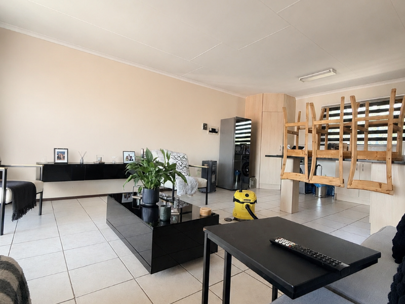Open-plan living and dining area featuring neutral tiled flooring and built-in cabinetry, offering a versatile space for modern apartment living.