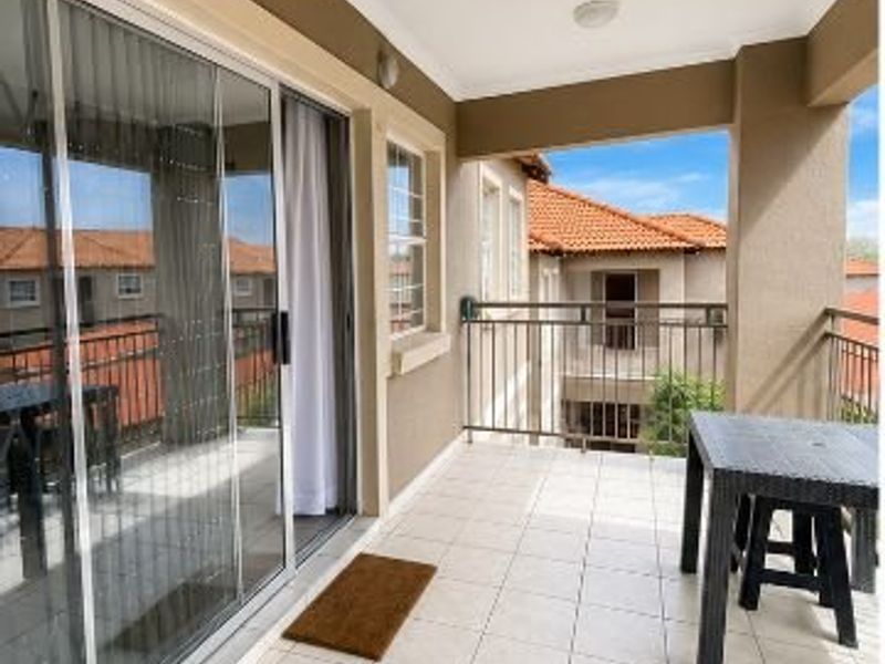 A covered balcony featuring tiled flooring, a metal balustrade, and large sliding glass doors providing access to the interior living space.
