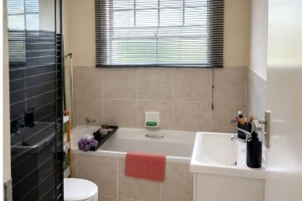 A functional bathroom featuring a built-in bathtub, vanity basin, toilet, and a separate shower enclosure with modern tiled finishes.