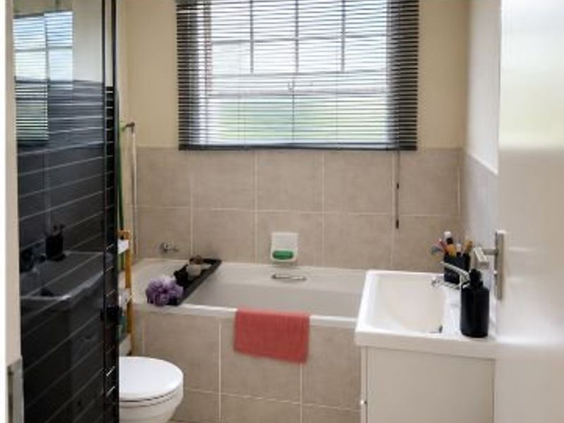 A functional bathroom featuring a built-in bathtub, vanity basin, toilet, and a separate shower enclosure with modern tiled finishes.