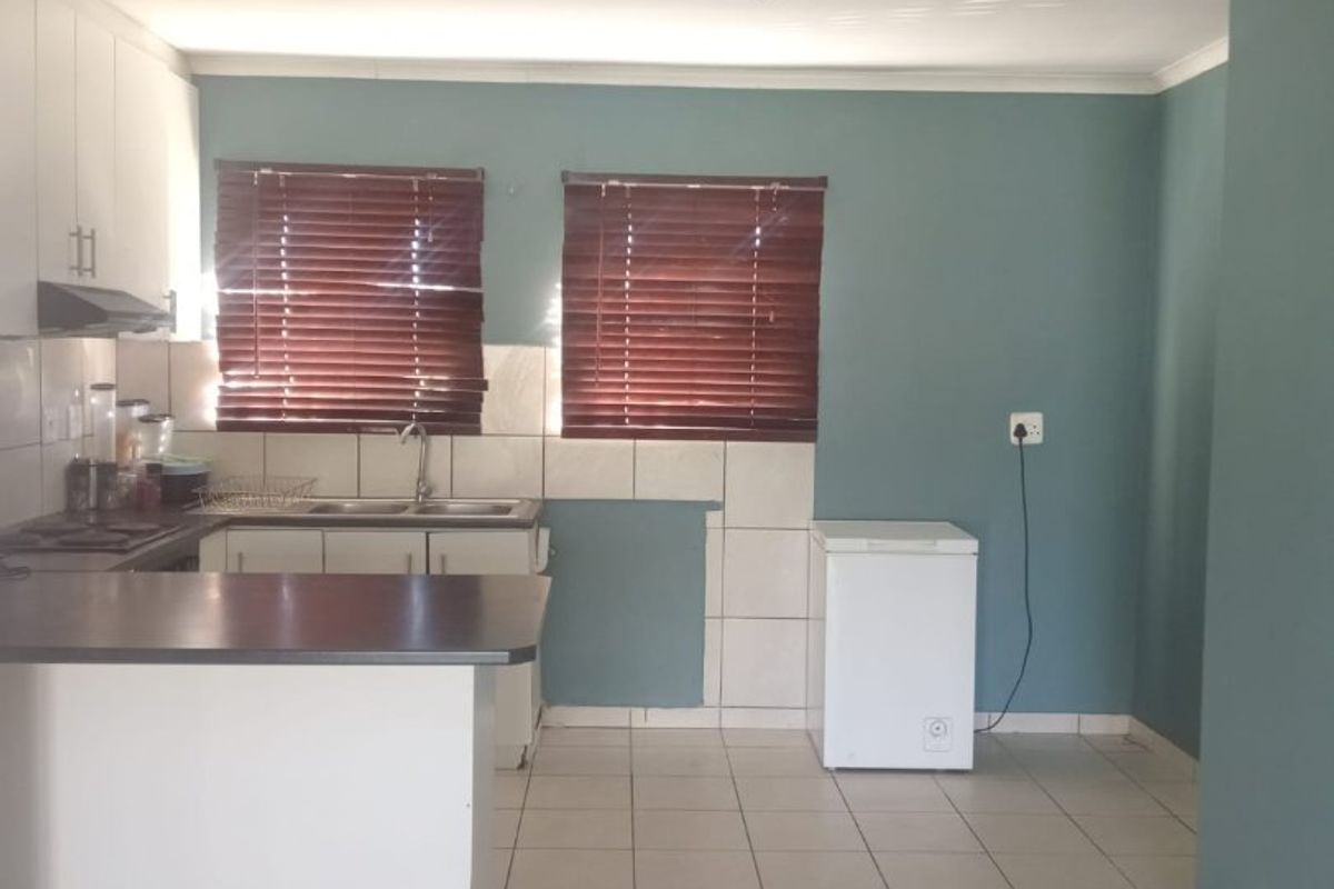 A functional kitchen featuring built-in cabinetry, laminate countertops, a stainless steel sink, and tiled flooring, offering a practical layout for daily use.