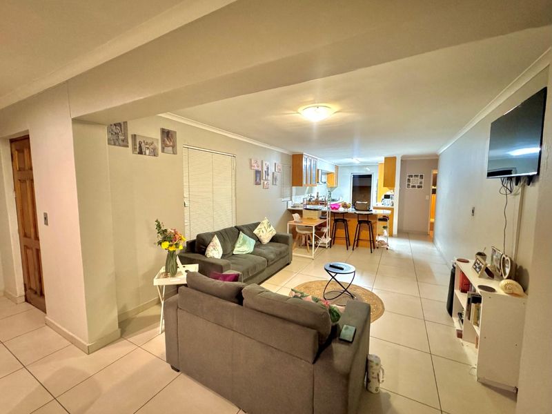 Open-plan living and kitchen area featuring tiled flooring, neutral wall finishes, and a functional kitchen island with breakfast bar seating.