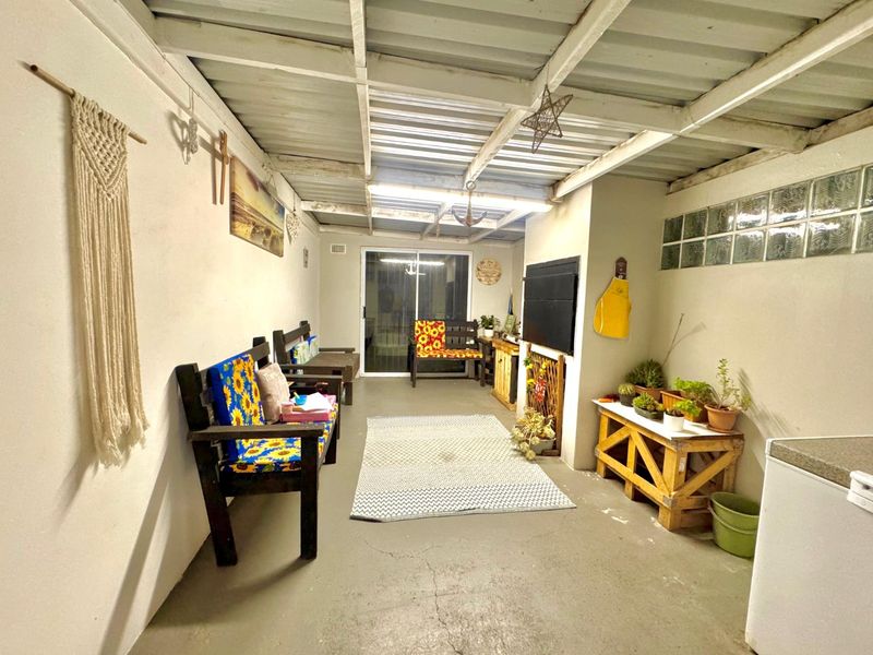 A covered outdoor patio area featuring a corrugated metal roof, exposed rafters, and a sliding glass door leading into the home.