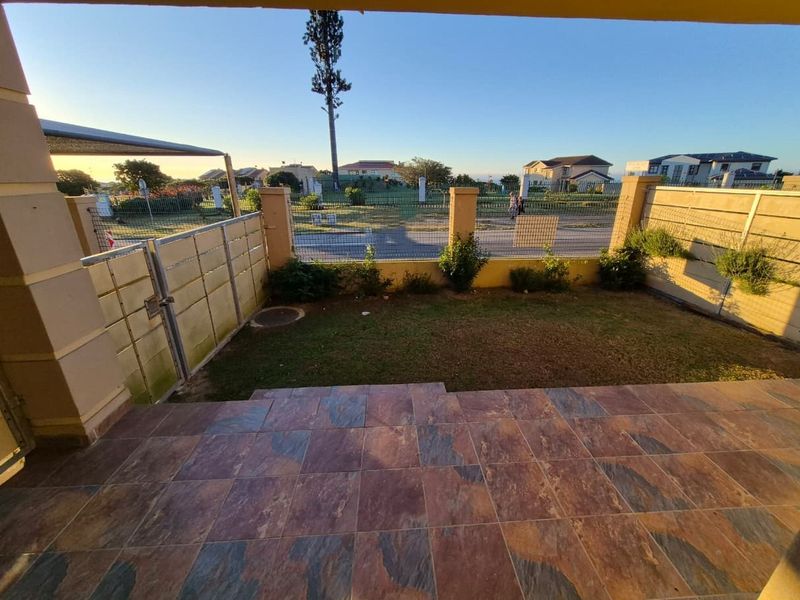 A private outdoor patio area featuring tiled flooring, a small lawn, and secure perimeter walling, offering a functional space for outdoor relaxation.