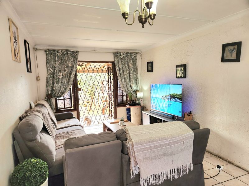 A living room featuring tiled flooring, a ceiling light fixture, and a security gate leading to the exterior.