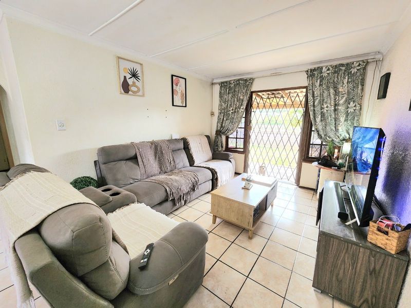 A living room featuring tiled flooring and a security gate leading to the exterior, with visible wear on the ceiling and walls.