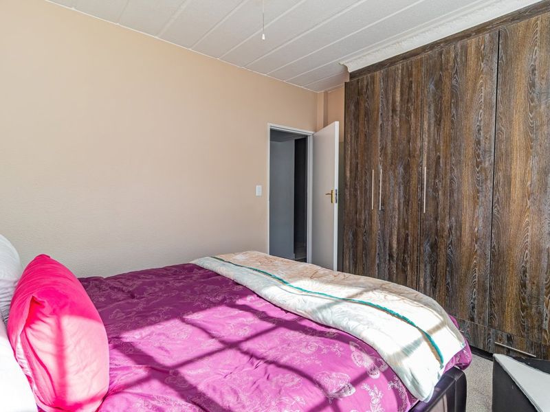 A bedroom featuring floor-to-ceiling built-in wooden cupboards and a textured ceiling finish.
