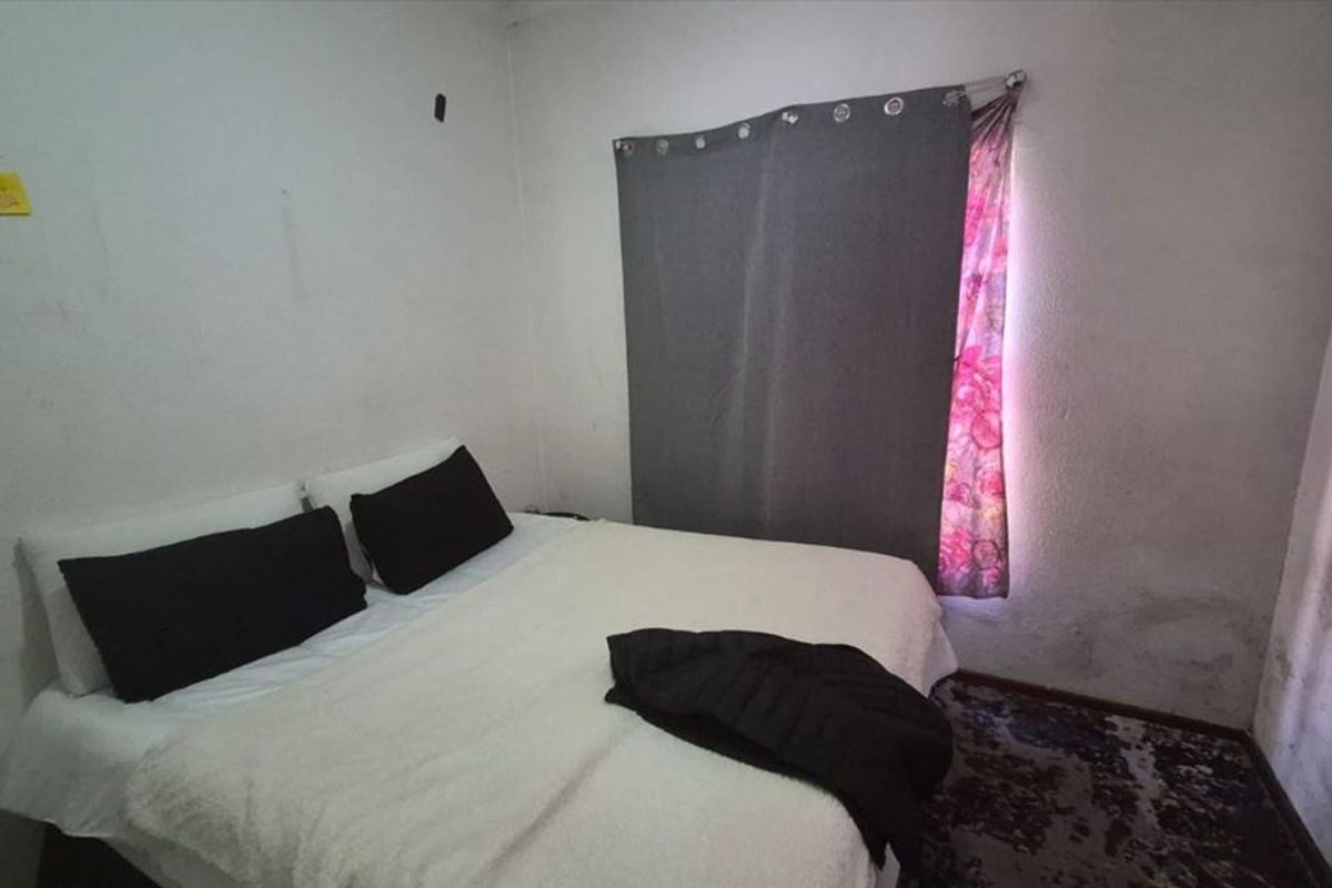 A bedroom featuring plain walls with visible surface wear and staining, requiring cosmetic attention and refurbishment.