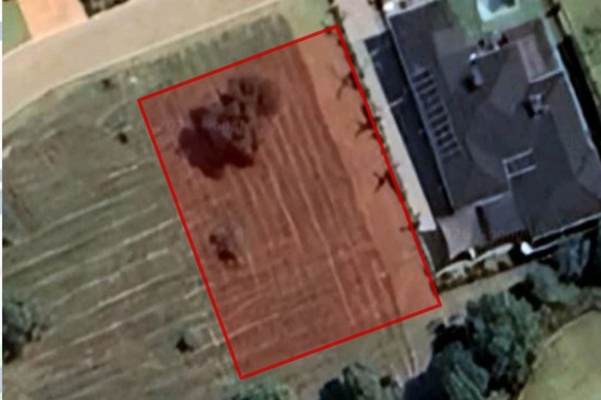 An aerial view of a vacant residential land plot with boundary markings, situated in a developed neighborhood.
