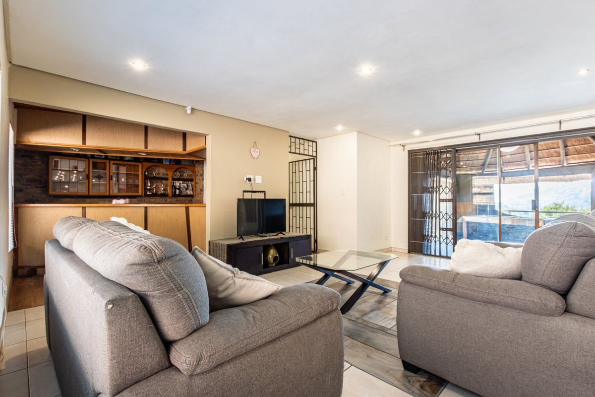 Spacious living room featuring a built-in bar area, recessed lighting, and large sliding glass doors leading to an outdoor space.